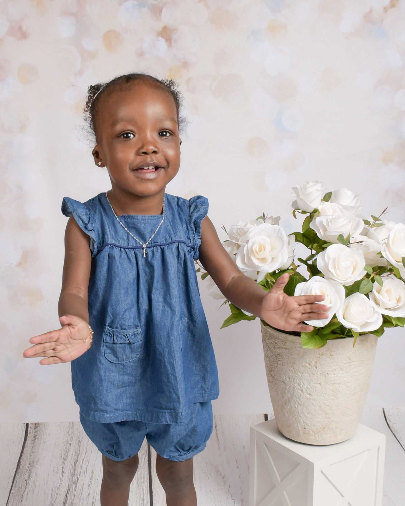 Renee Fontenot smiling in a denim outfit next to white roses
